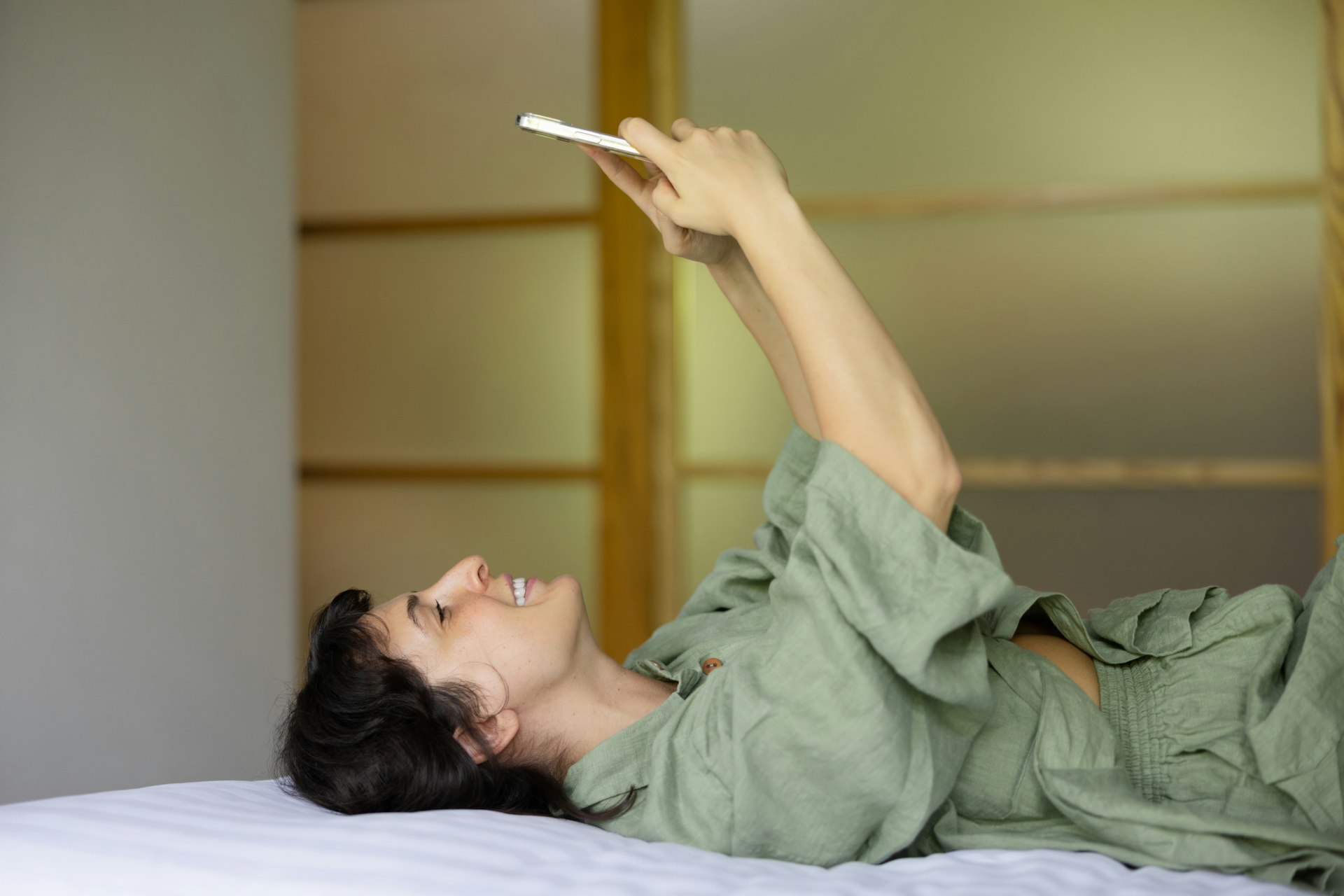 a woman laying on top of a bed holding a cell phone